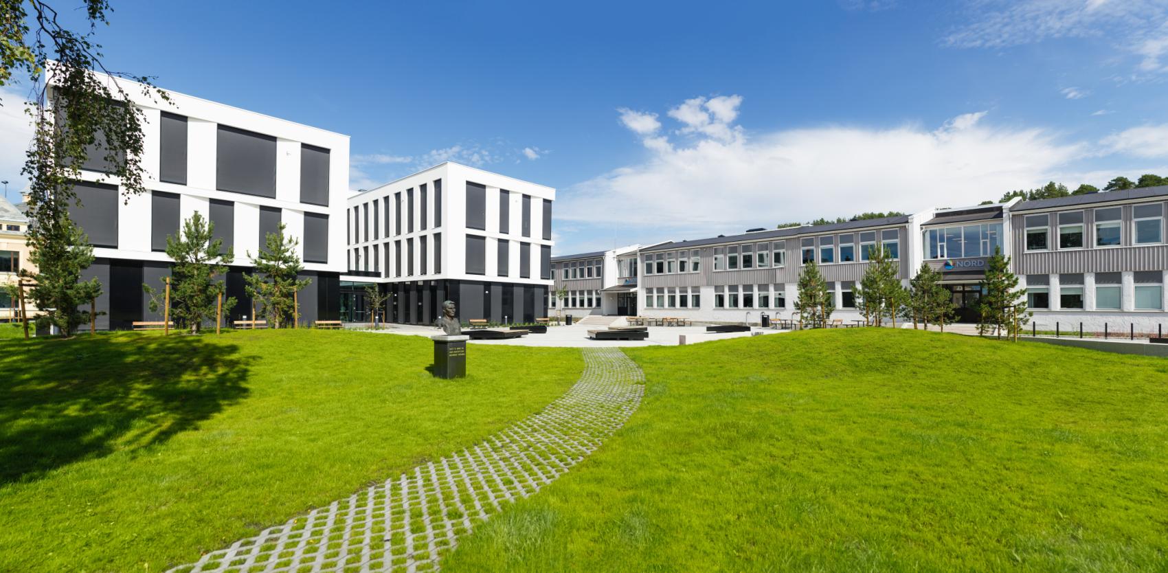 Stort, hvitt bygg på en grønn plen. Foto.